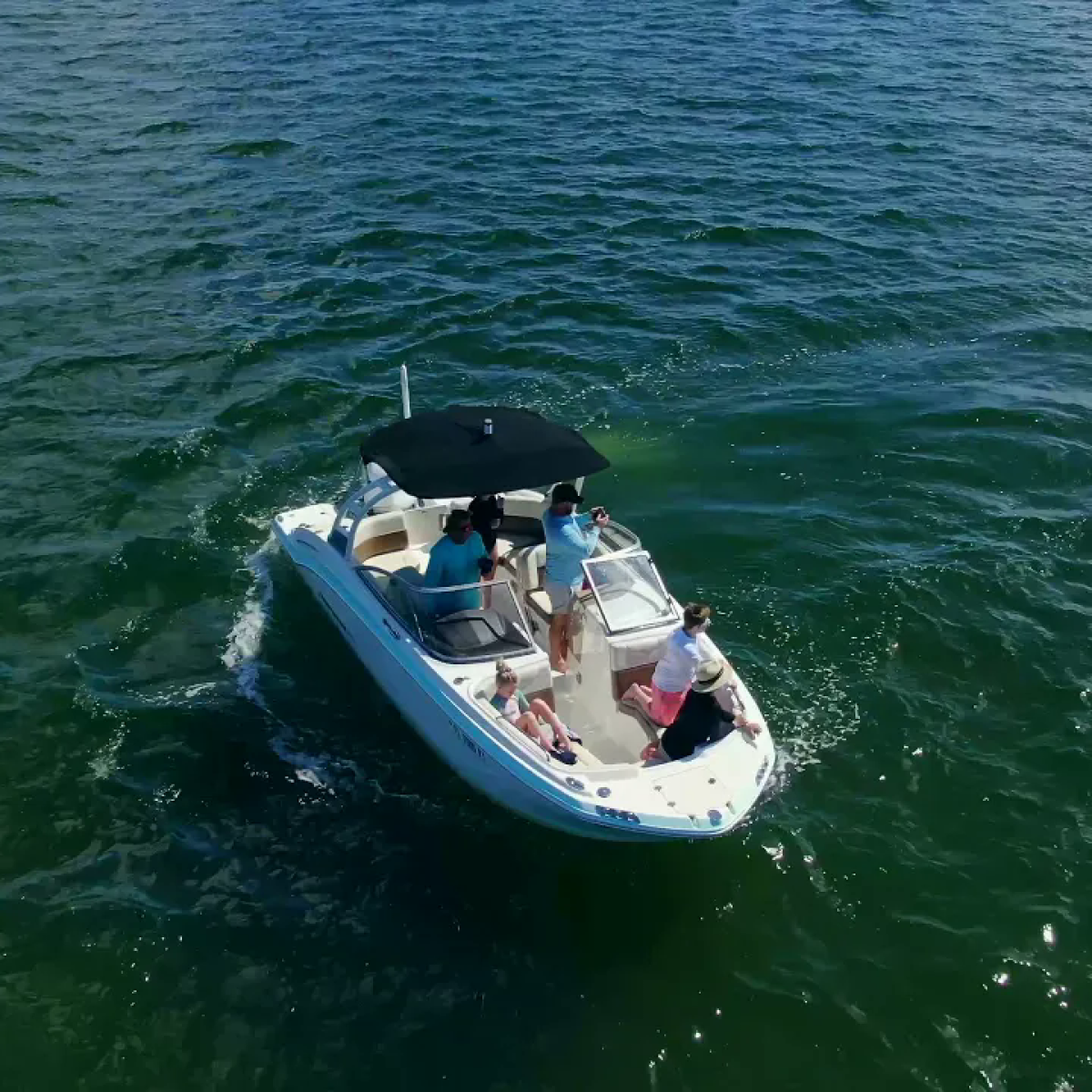 Small boat on open water with people and an umbrella.