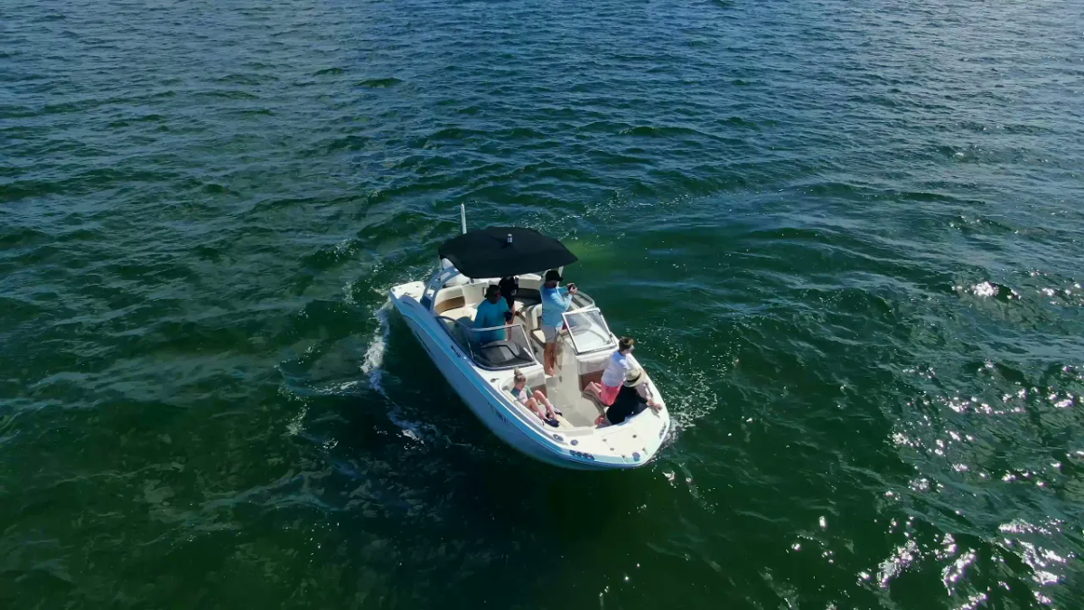 Small boat on open water with people and an umbrella.
