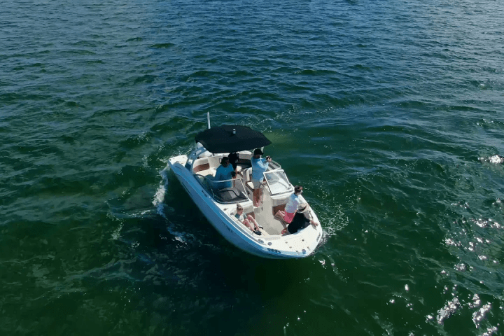 Small boat on open water with people and an umbrella.