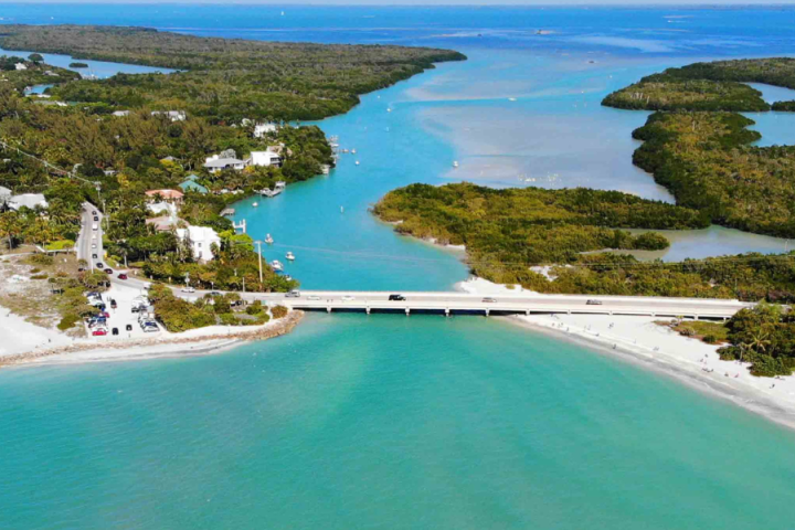 Aerial view of a bridge over turquoise water between lush green islands.